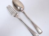 two forks and a spoon on a white table