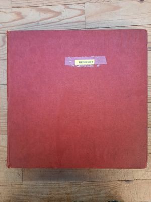 une boîte rouge sur laquelle est collé un autocollant, posée sur un plancher en bois