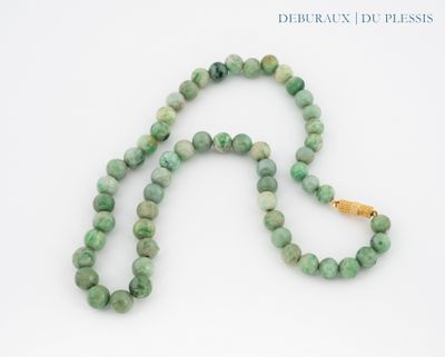 collier composé de perles de jade vert avec un fermoir en or, sur fond blanc