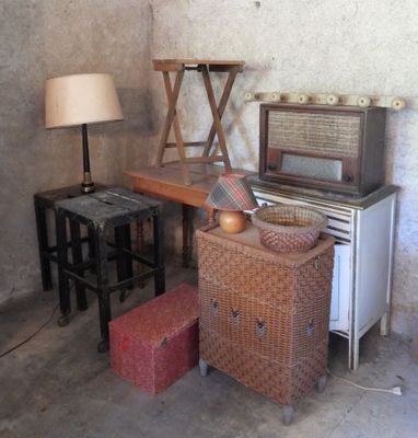 a table with a lamp, a chair, and an old radio in a room