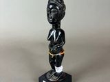 a black figurine of a woman with a basket on her head