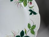 a white plate with green leaves and flowers on it