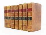 six vieux livres sont alignés sur une surface blanche
