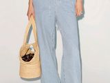 une femme vêtue d'un haut blanc et d'un pantalon bleu, tenant un sac en paille