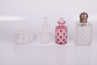 three glass bottles and a small glass container on a white surface