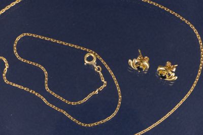 un ensemble composé d'un collier et de boucles d'oreilles en or sur fond bleu