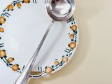 a plate with a spoon and a plate with oranges on it