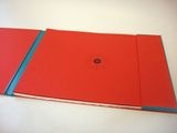 a red book with a blue cover sitting on a table