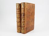 two old books sitting on top of each other on a white surface