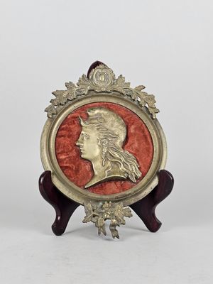 an image of a gold and red medallion with a woman ' s head