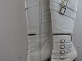 pair of white high heel boots with buckles on a black table