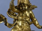 gold statue of a woman holding a fan on top of a clock tower