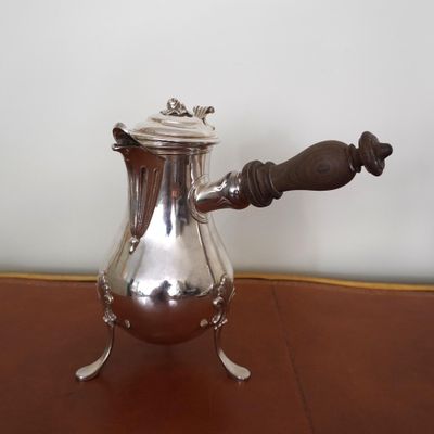 a silver coffee pot on a table with a wooden handle