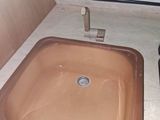 a brown sink in the corner of a small bathroom