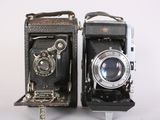two old cameras sitting side by side on a white surface