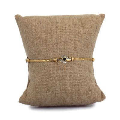 the gold chain bracelet is attached to a pillow on a white background