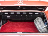 a red car with its trunk open and a tire in the trunk