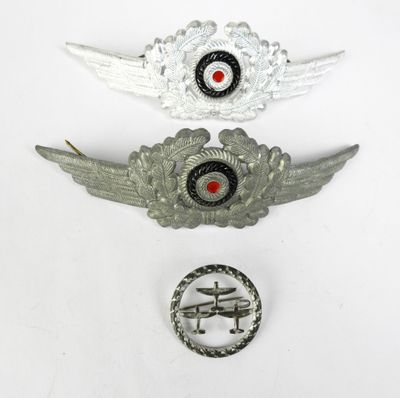 deux insignes métalliques argentés et un œil rouge sur un fond blanc