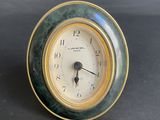 a green and gold clock sitting on a table