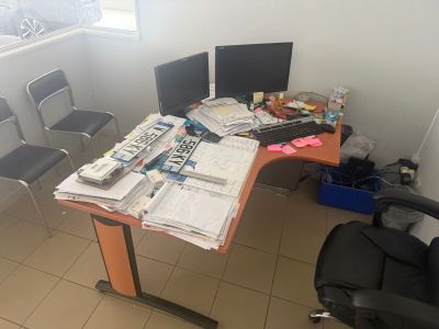 un bureau sur lequel se trouvent deux écrans d'ordinateur et beaucoup de papiers