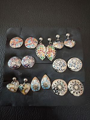 several pairs of earrings are displayed on a black surface