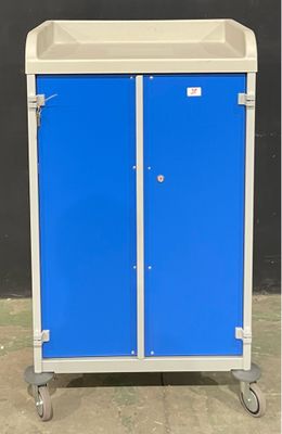 une armoire bleue et blanche à deux portes, montée sur roulettes, devant un mur noir