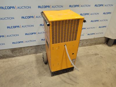 un climatiseur jaune posé sur un sol en béton, près d'un mur
