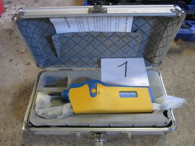 un outil jaune et bleu dans un coffret posé par terre