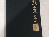 un livre noir portant des inscriptions en chinois, posé à côté d'un ordinateur portable