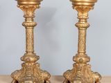 pair of antique brass candlesticks on wooden table against blue wall