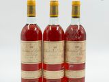 trois bouteilles de vin posées les unes à côté des autres sur une surface blanche