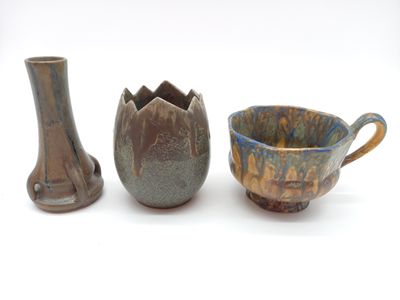 three pieces of pottery sitting next to each other on a white surface