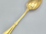 a gold spoon with a handle on a white surface