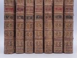 several old books are lined up in a row on a white surface