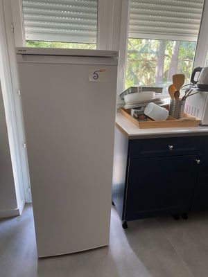 un réfrigérateur blanc dans une cuisine, près d'une fenêtre