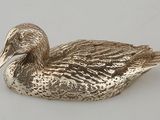 un canard argenté posé sur une surface blanche