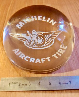 une boule de verre portant un logo, à côté d'une règle