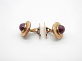a pair of gold cufflinks with garnets on them