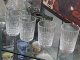 bottles and glasses on a glass shelf in a glass case