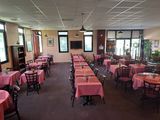 Ce restaurant compte de nombreuses tables et chaises recouvertes de nappes roses.