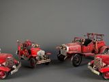 four red fire trucks are lined up in a row on a gray surface