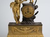 une statue en or représentant une femme tenant un oiseau et une horloge