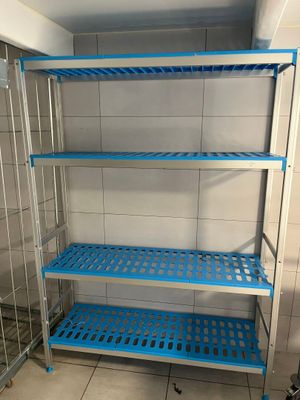 des étagères en plastique bleu dans une salle de bains aux murs et au sol carrelés
