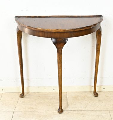 une petite table en bois au plateau incurvé, posée sur un sol carrelé