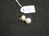 une paire de boucles d'oreilles en perles blanches posées sur un fond noir, avec une étiquette de prix
