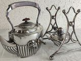 two silver teapots sitting on a stand on a table