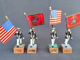 three figurines of soldiers holding flags and standing on wooden bases