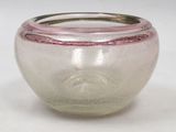 a small glass bowl with a silver rim on a white surface