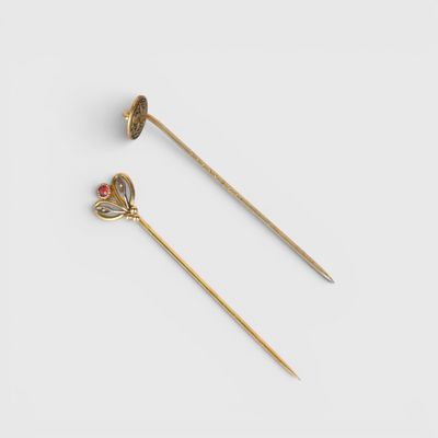 a pair of gold plated hair pins with red stones