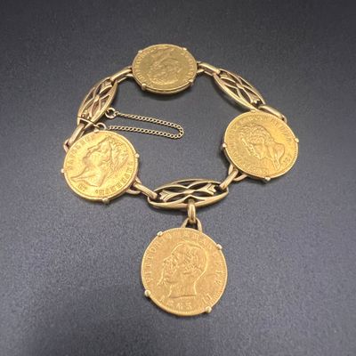 un gros plan d'un bracelet composé de pièces d'or posé sur une surface noire